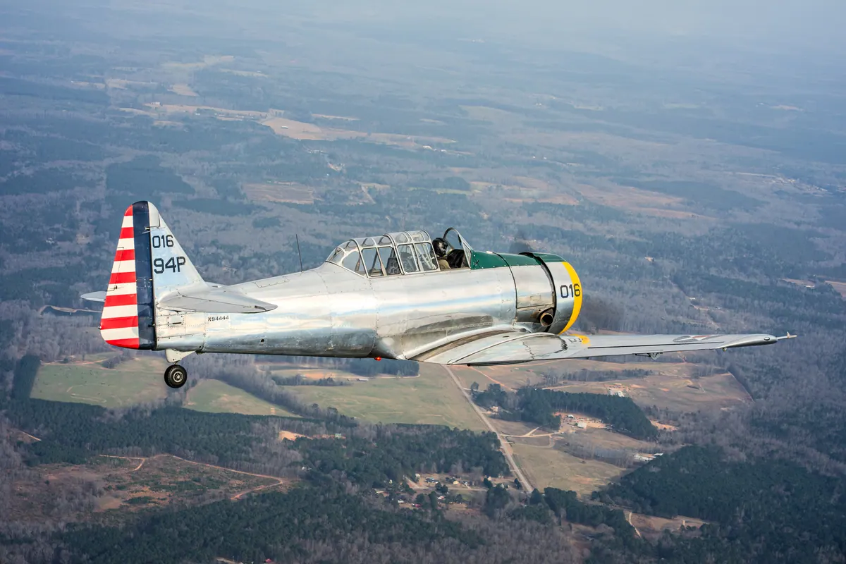 The polished silver trainer '016' flying across patchwork farmland and woods seen from above
