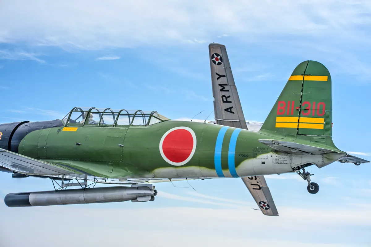The green 'Kate' torpedo-bomber replica close in front of the silver trainer, whose 'ARMY' wing and star insignia show behind