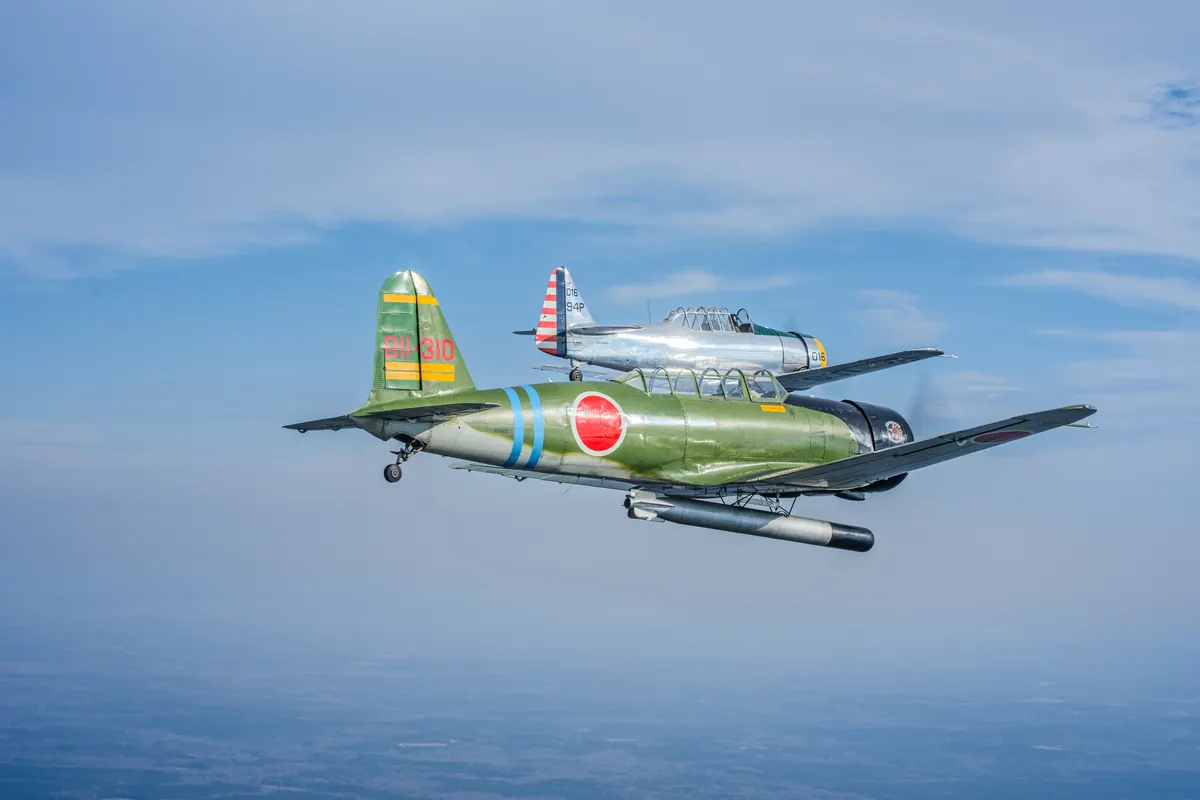 The green 'Kate' torpedo-bomber replica and the silver trainer stacked close together, seen nearly head-on