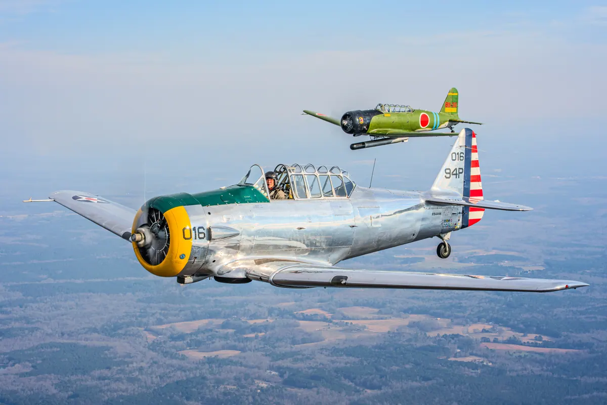 The polished silver trainer '016' flies toward the camera with the green 'Kate' torpedo-bomber replica close above and behind