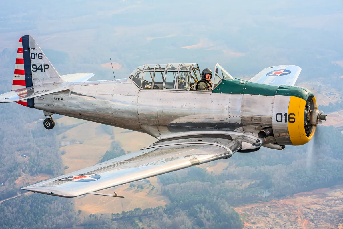 The polished silver trainer '016' in full profile above farmland, star insignia on the wing
