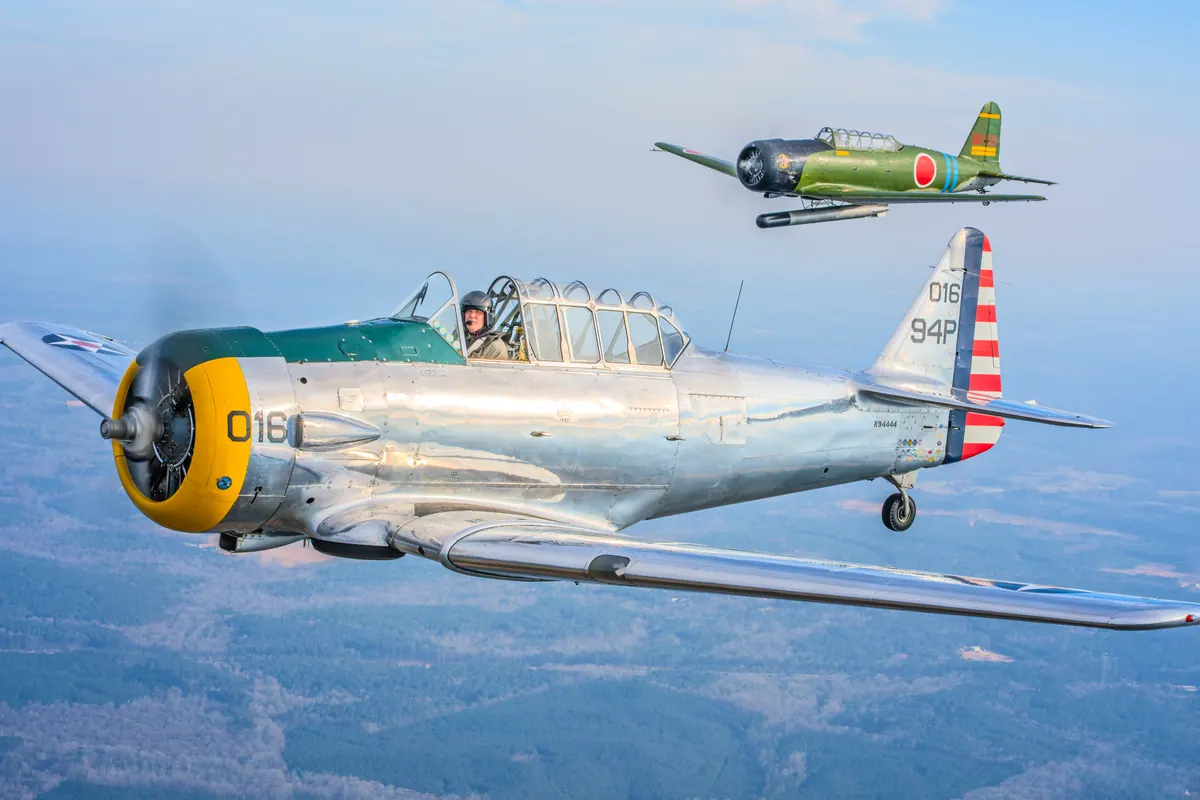 The polished silver trainer '016' flies toward the camera with the green 'Kate' torpedo-bomber replica small and high behind