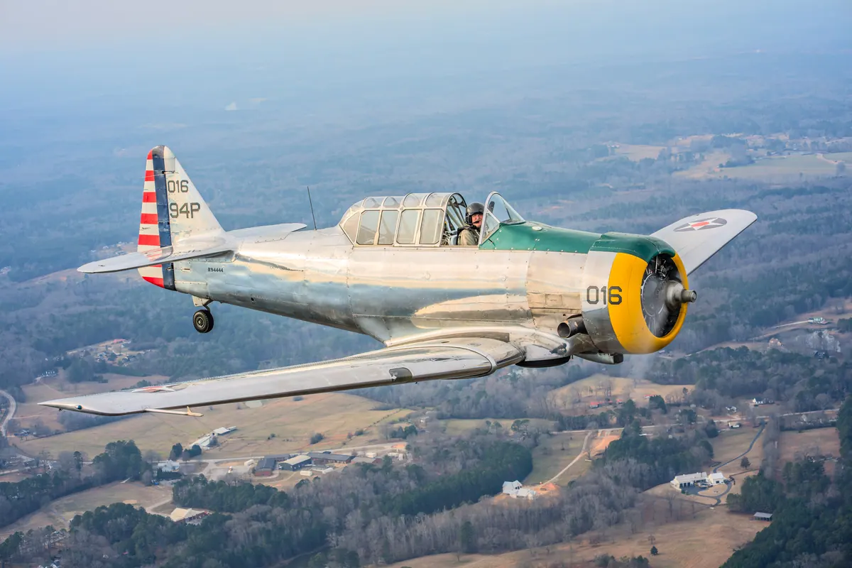 The polished silver trainer '016' seen from above, flying over farms and woods
