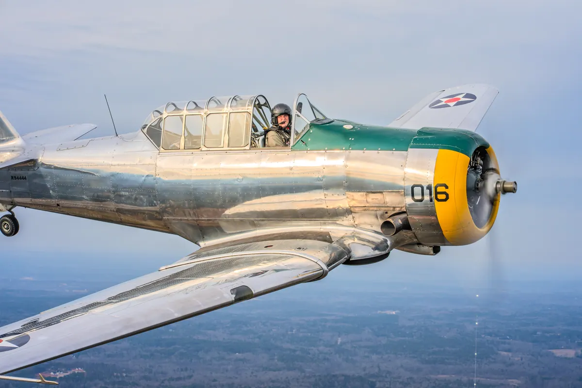 Tight side view of the polished silver trainer '016' against a pale blue sky
